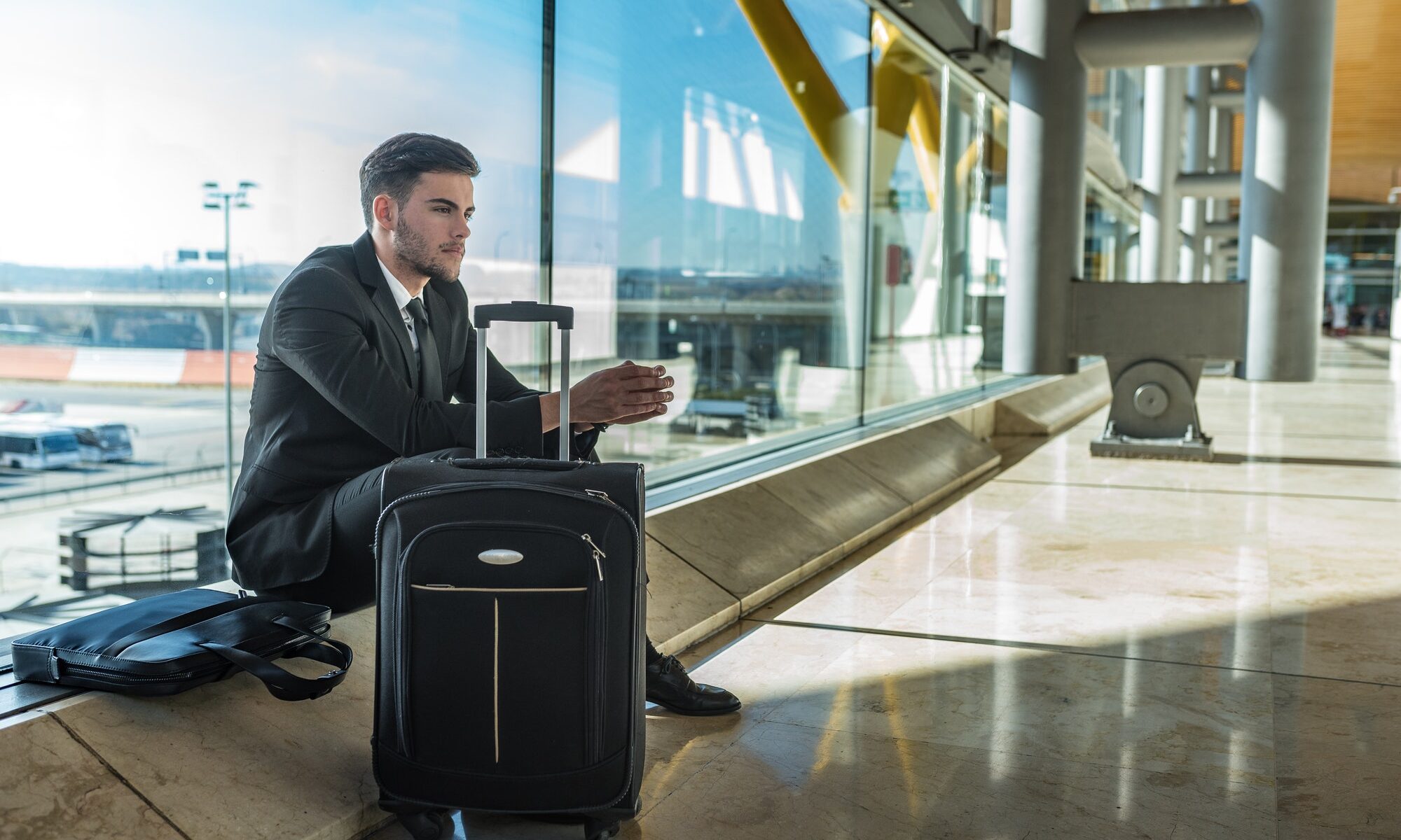young businessman upset at the airport waiting his delayed flight with luggage