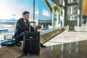 young businessman upset at the airport waiting his delayed flight with luggage